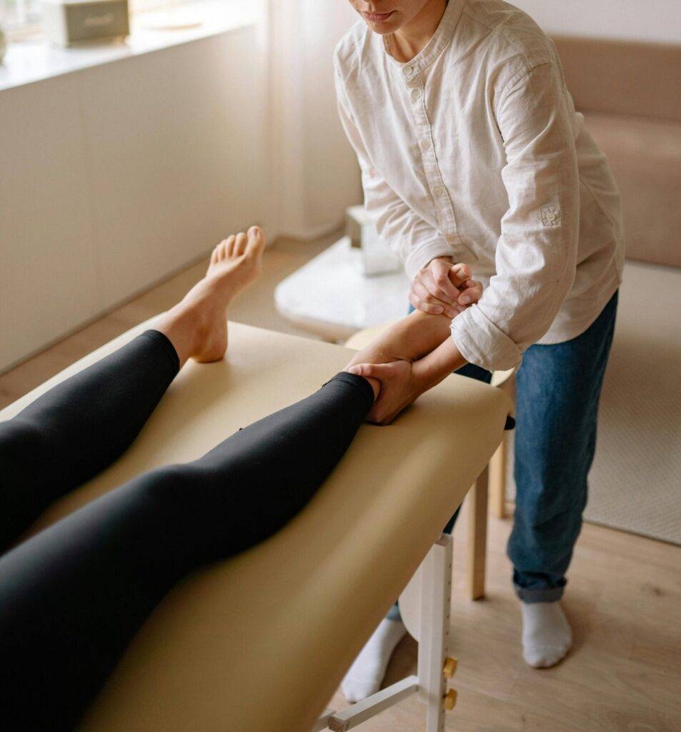 A therapist provides a leg massage to a woman in a calm, serene indoor environment.